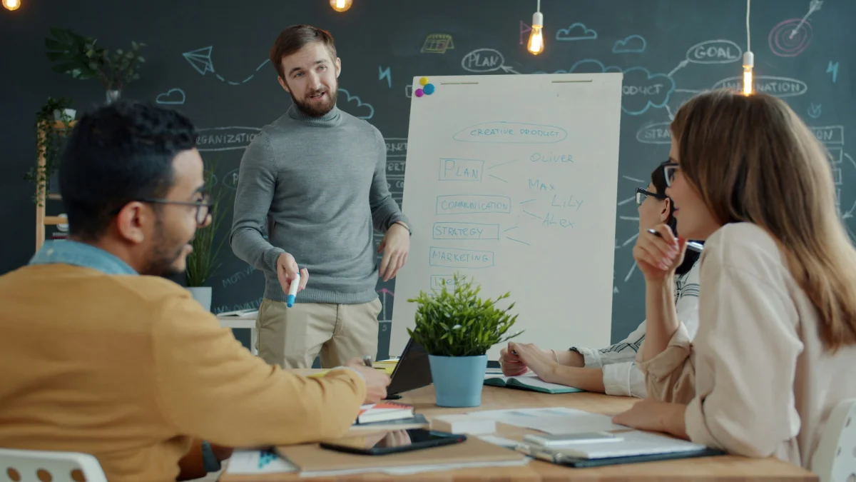 Team reviewing a project roadmap and task breakdown on a whiteboard during a planning session