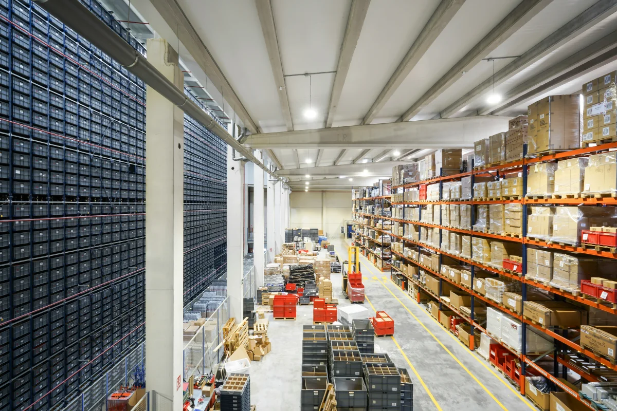 Warehouse aisle with pallet racking, stacked boxes and a forklift inside a fulfillment center